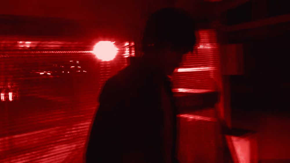 Still from the Fake ID video: a dark parking garage lit by a camera flash